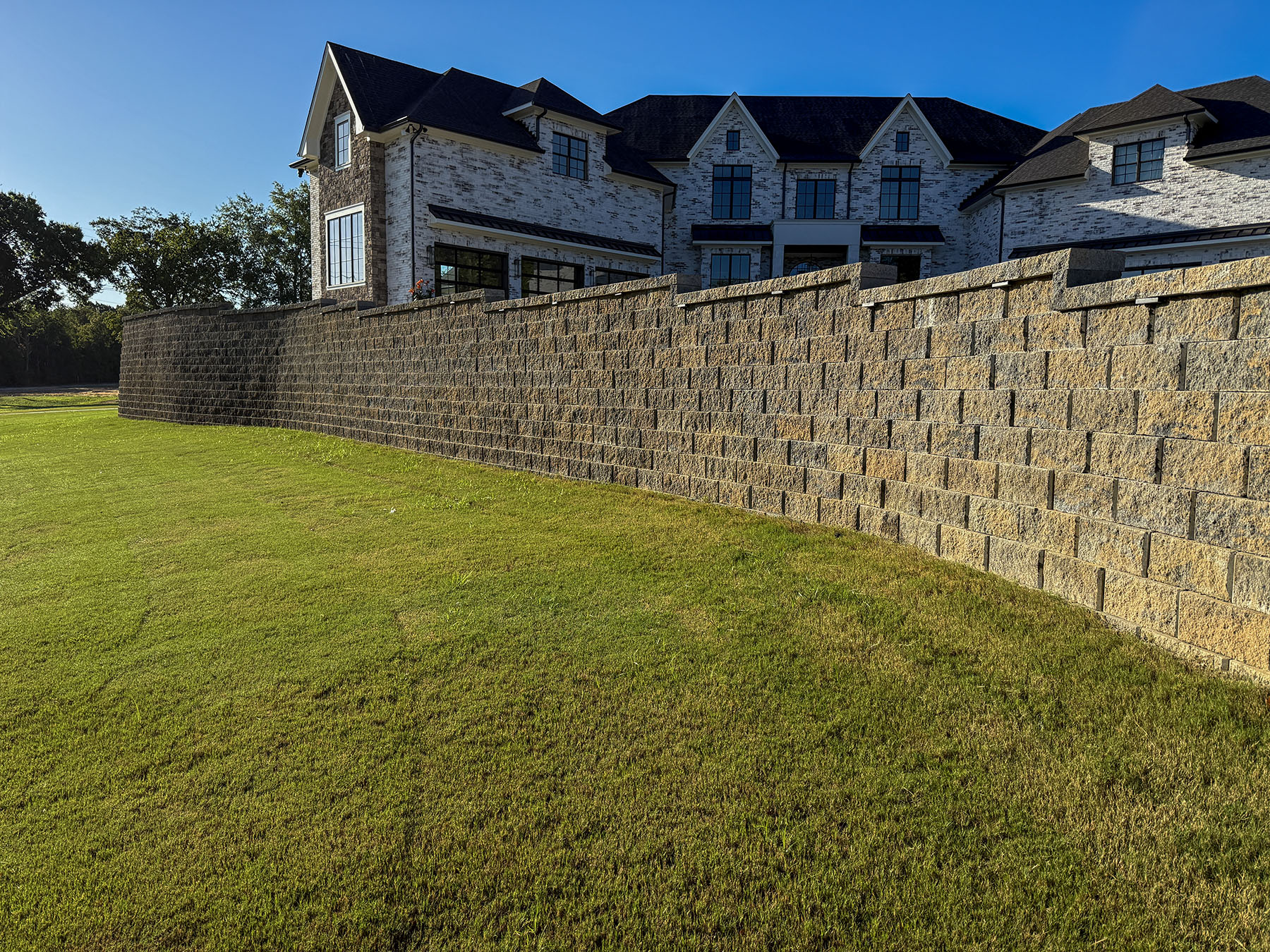 Segmental block retaining wall bordering a lawn below a residence